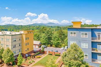 A view of a hotel with a parking lot in front and a mountain in the background.